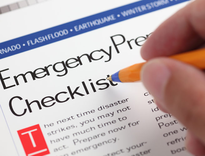 Emergency Checklist and hand with ballpoint pen. Close-up.