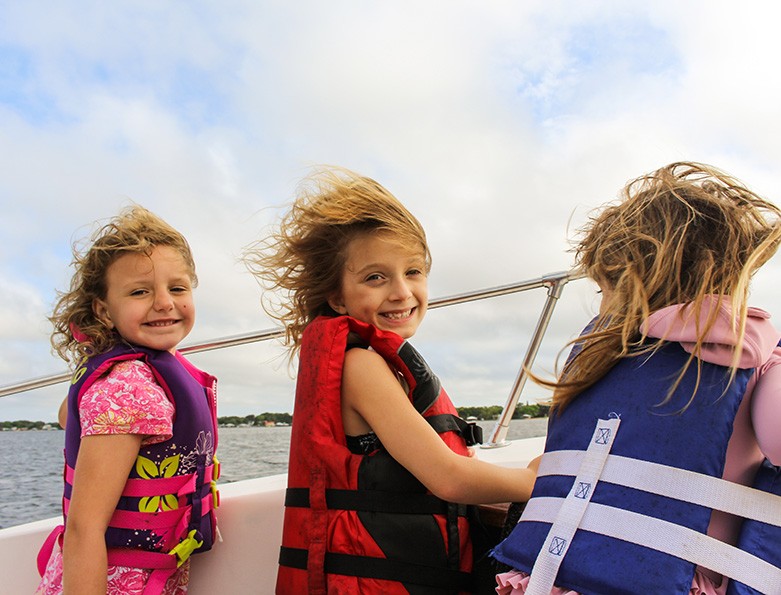 Three little girls wear life jackets on a boat